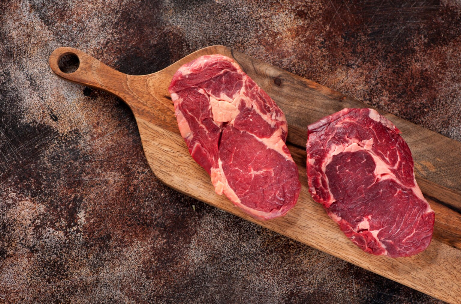 Nötlådan - 10 kg 1 Raw ribeye steak on a wooden board, top view